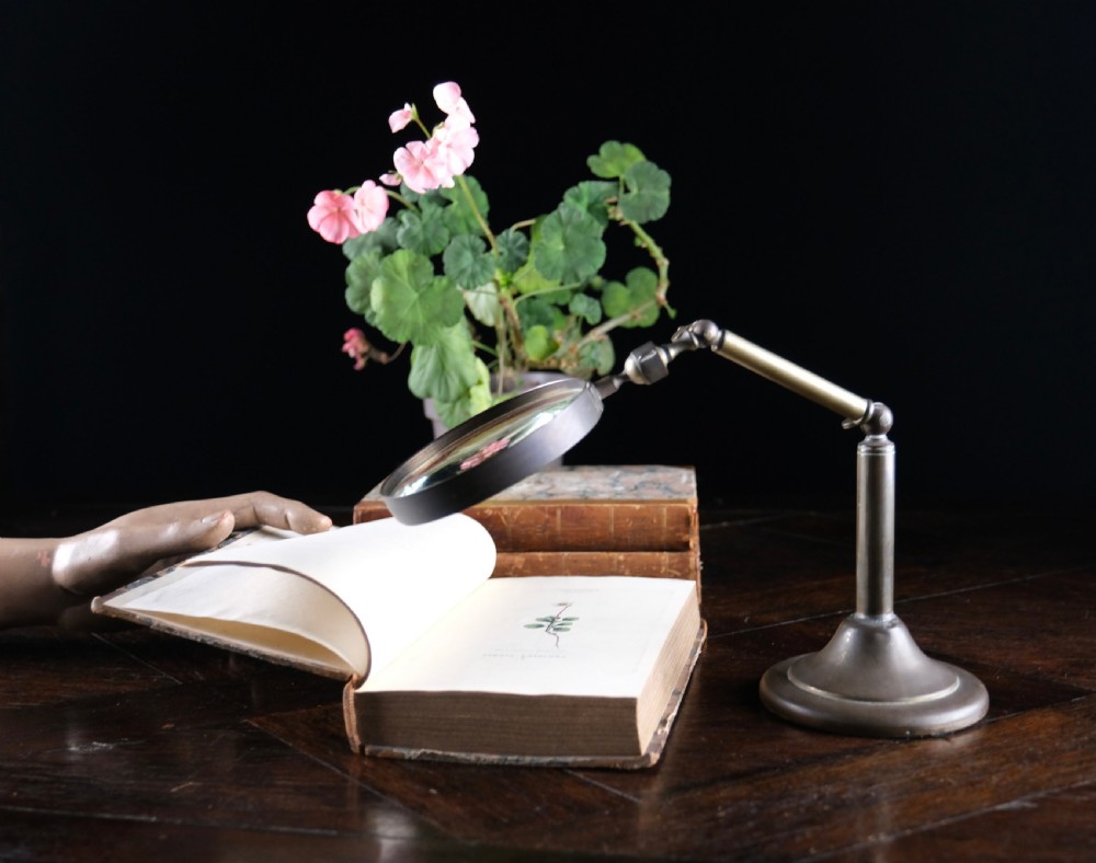 An antique Edwardian brass magnifying glass featuring an adjustable articulated arm and a circular weighted base. View II