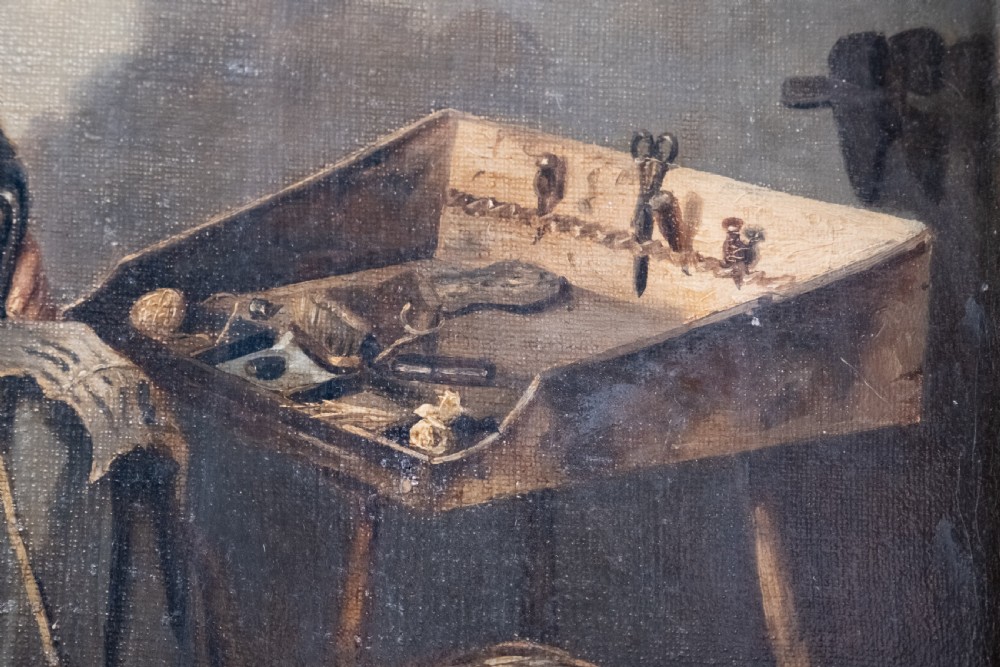 A 19th-century oil painting depicting a seated cobbler working at a bench, encased within an ornate gilded frame with shell corner detailing. View VI