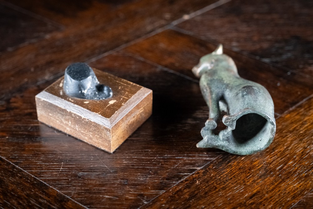 A dark patinated bronze figure of a seated Egyptian cat mounted on a wooden rectangular base. View VIII