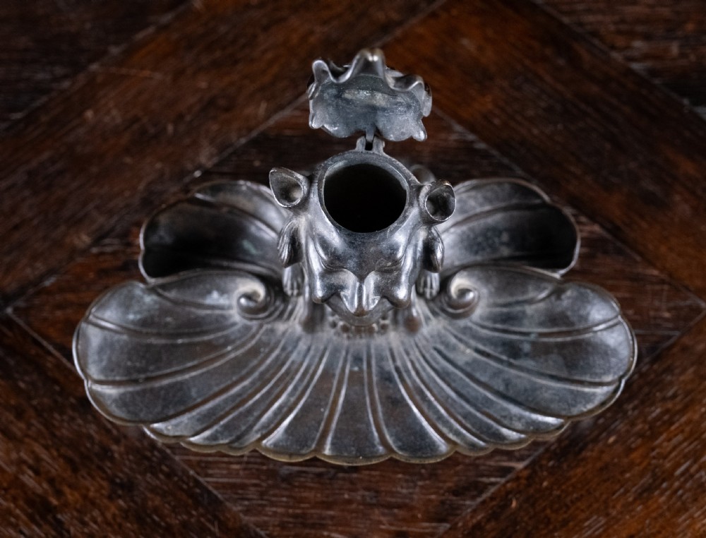 A 19th-century patinated bronze inkstand featuring a central sculpted grotesque face above a fluted pen tray raised on small paw feet. View II