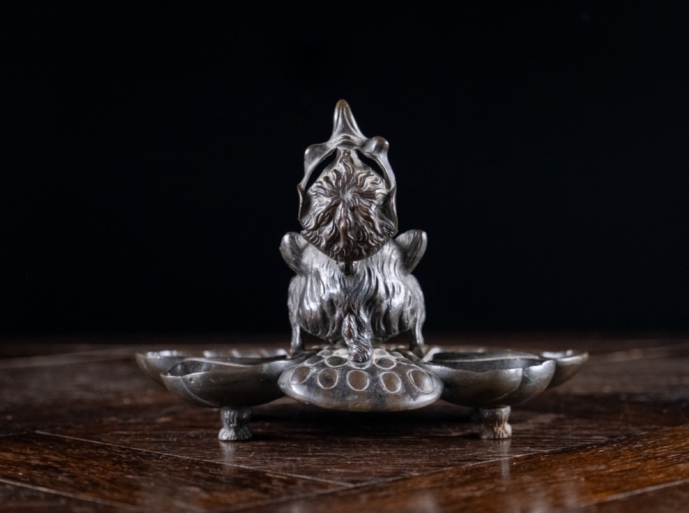 A 19th-century patinated bronze inkstand featuring a central sculpted grotesque face above a fluted pen tray raised on small paw feet. View III