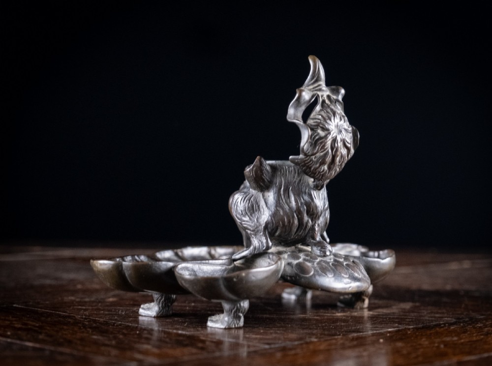 A 19th-century patinated bronze inkstand featuring a central sculpted grotesque face above a fluted pen tray raised on small paw feet. View IV