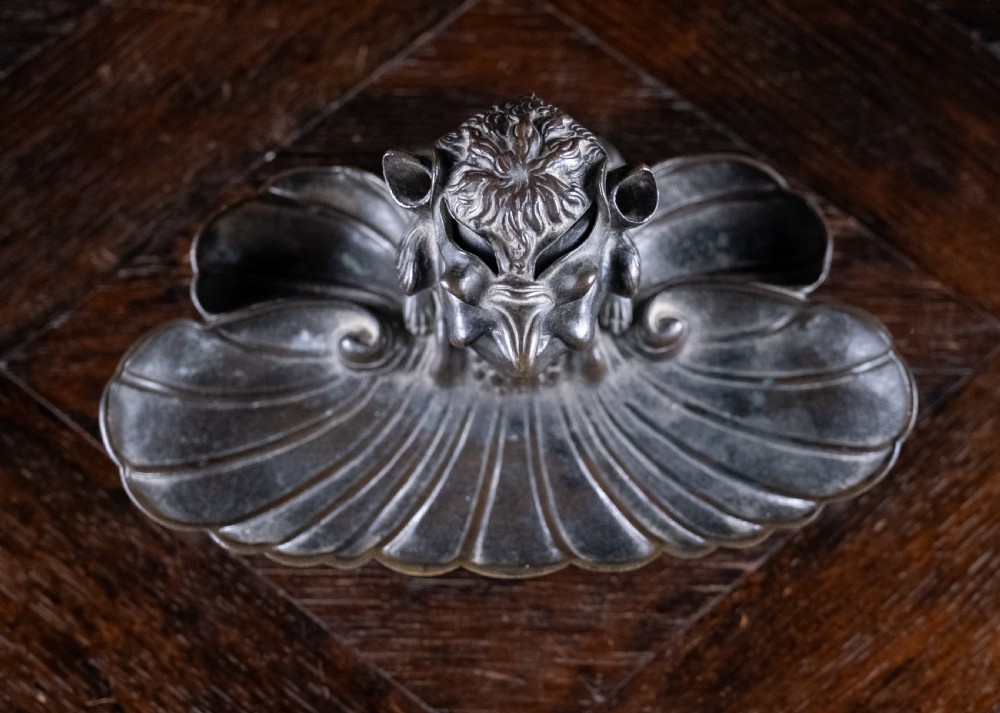 A 19th-century patinated bronze inkstand featuring a central sculpted grotesque face above a fluted pen tray raised on small paw feet. View V