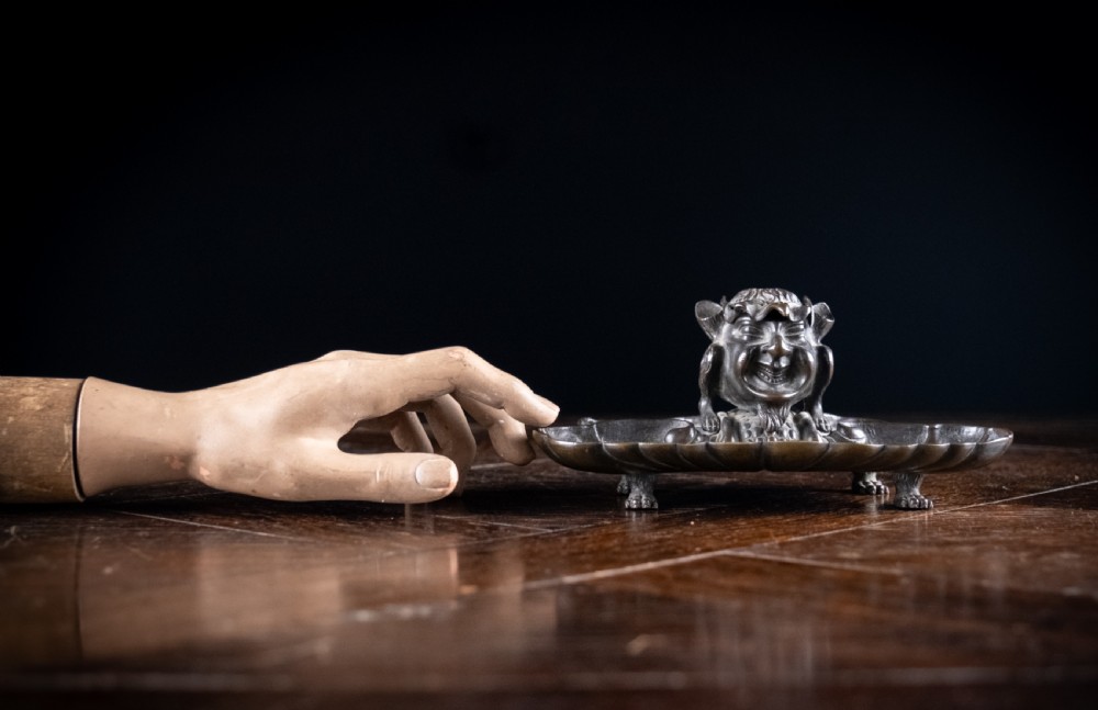 A 19th-century patinated bronze inkstand featuring a central sculpted grotesque face above a fluted pen tray raised on small paw feet. View XIII