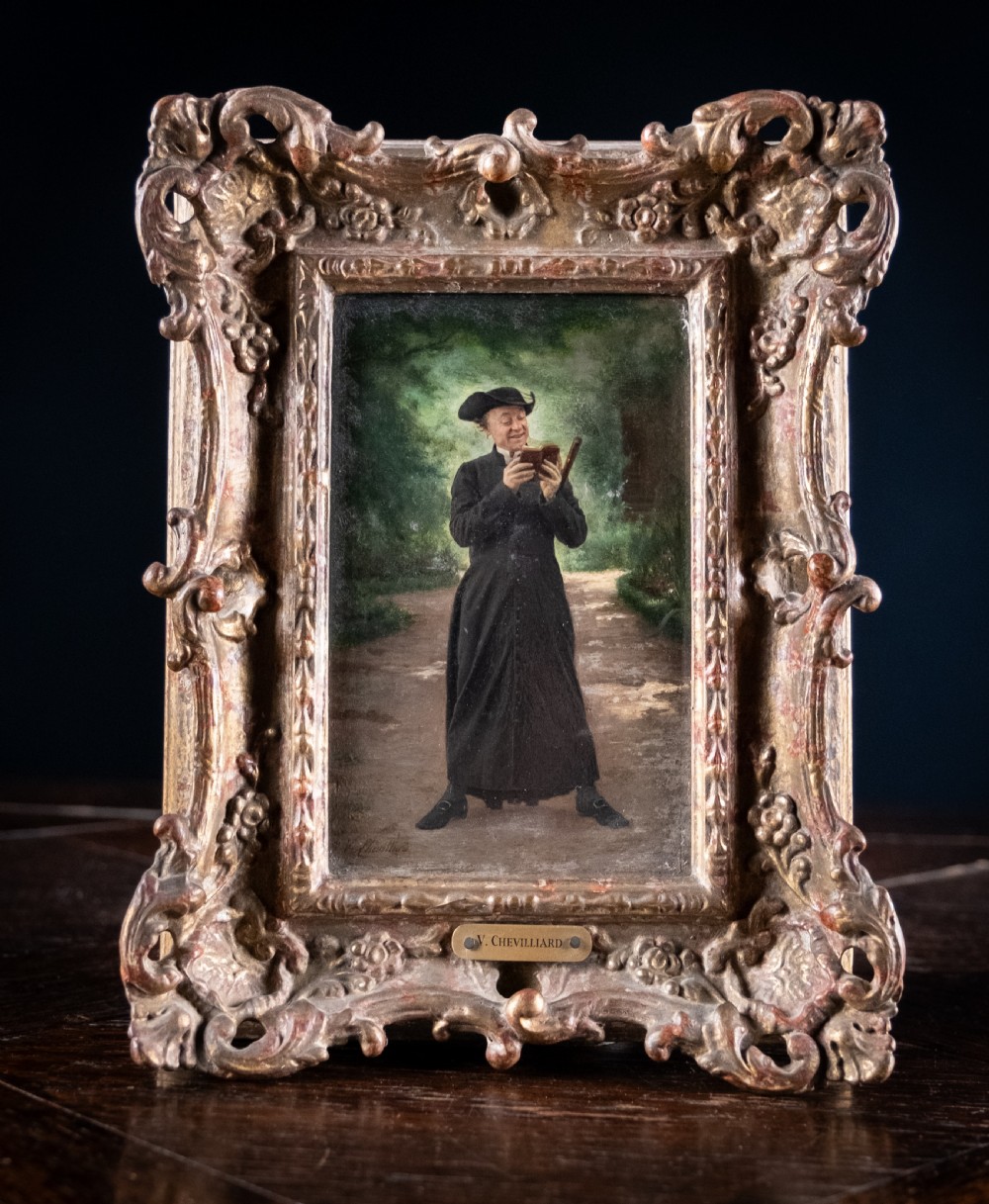 A 19th-century oil painting on panel depicting a smiling clergyman reading a book, set within a heavily carved rococo gilt frame.