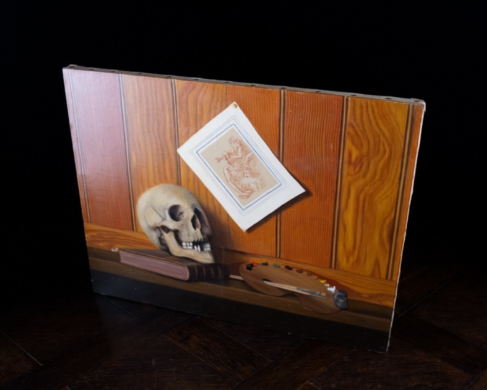 An oil painting depicting a human skull resting on a bound book alongside an artist palette, brushes, and a pinned sketch against a vertical timber panel background. View XI