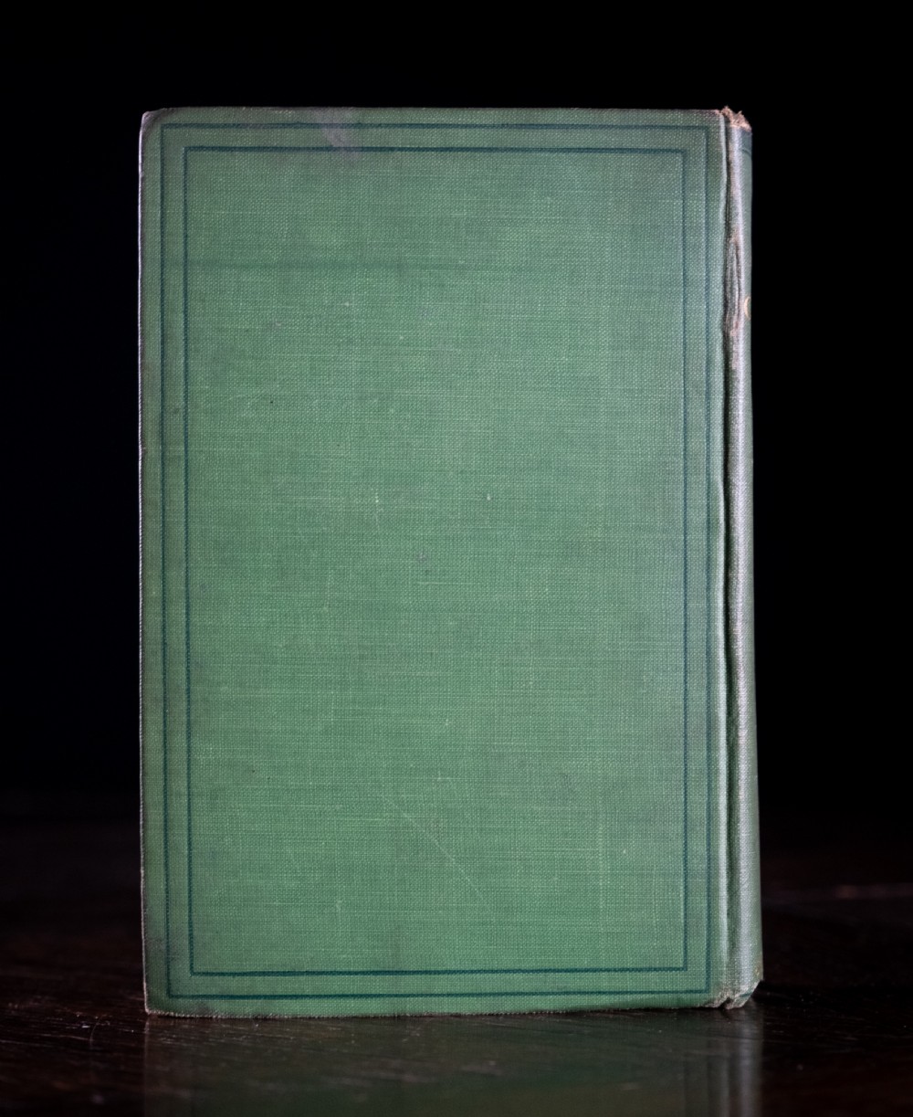 A green cloth-bound antique book standing vertically with gold embossed title lettering on the spine. View III
