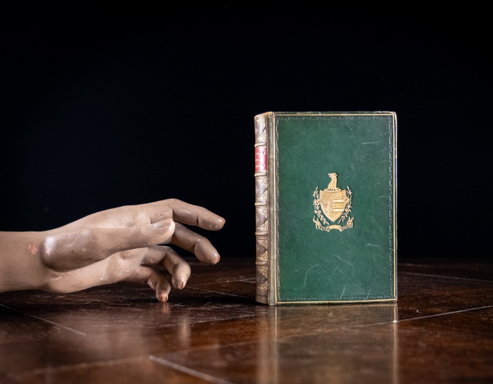 A Victorian leather-bound book standing upright, featuring green boards with a gilt crest and a brown leather spine decorated with gold tooling. View XIII