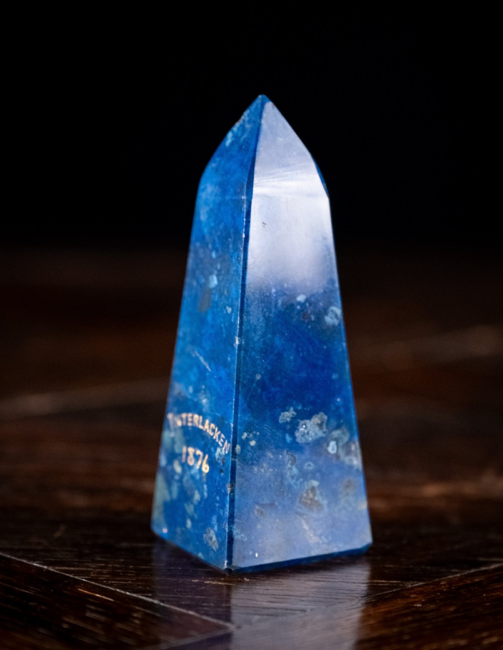 A polished deep blue lapis lazuli obelisk engraved with gilt text reading Interlacken 1876 near the base. View III