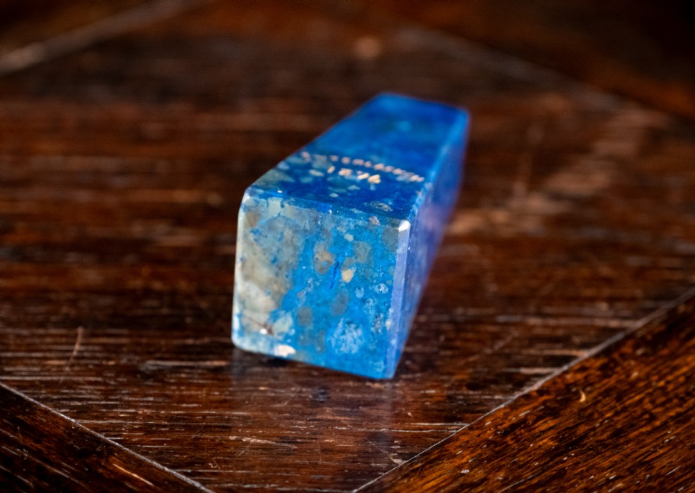 A polished deep blue lapis lazuli obelisk engraved with gilt text reading Interlacken 1876 near the base. View VII