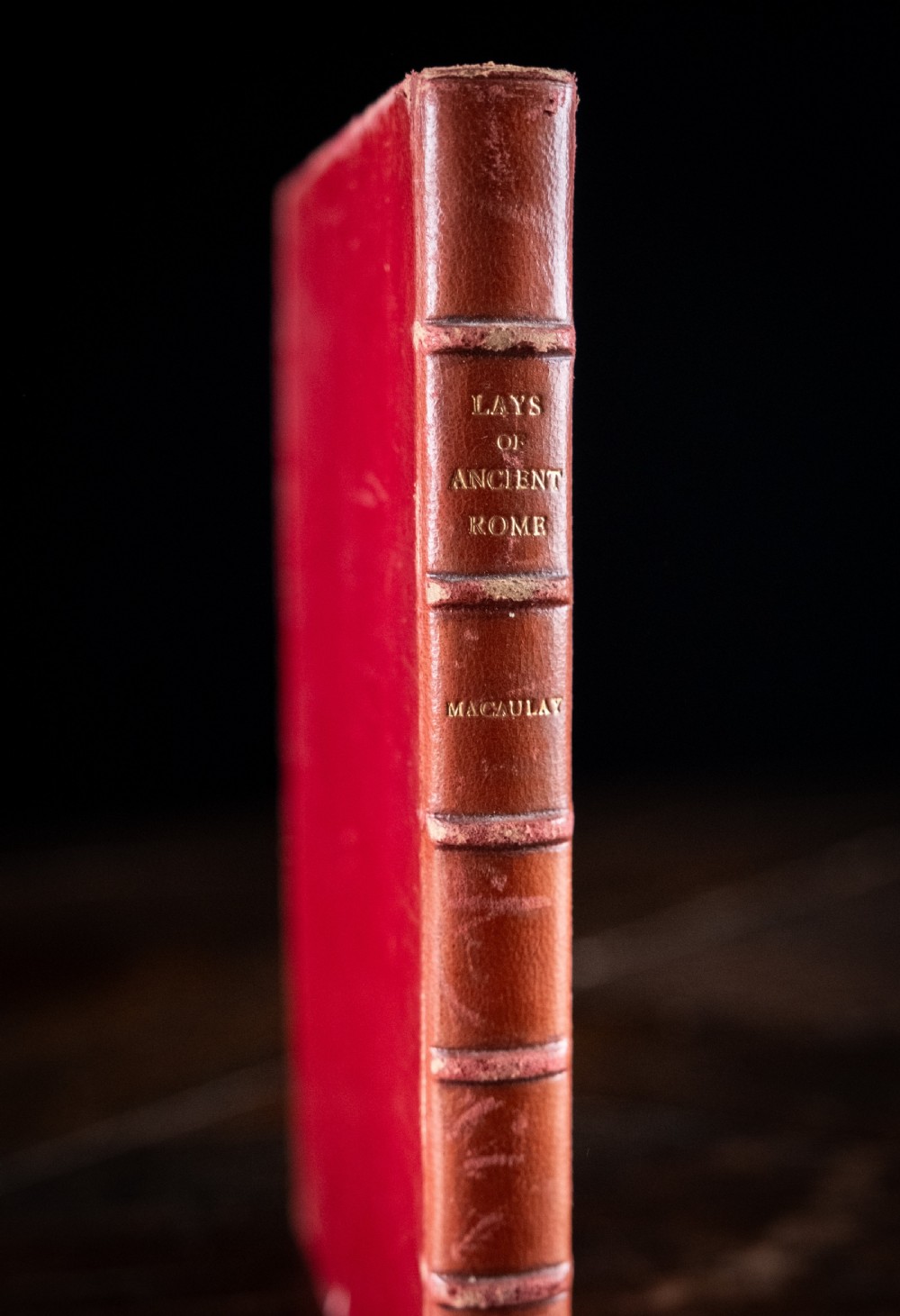 A red leather-bound edition of Lays of Ancient Rome by Macaulay, featuring raised spine bands and gilt lettering. View II