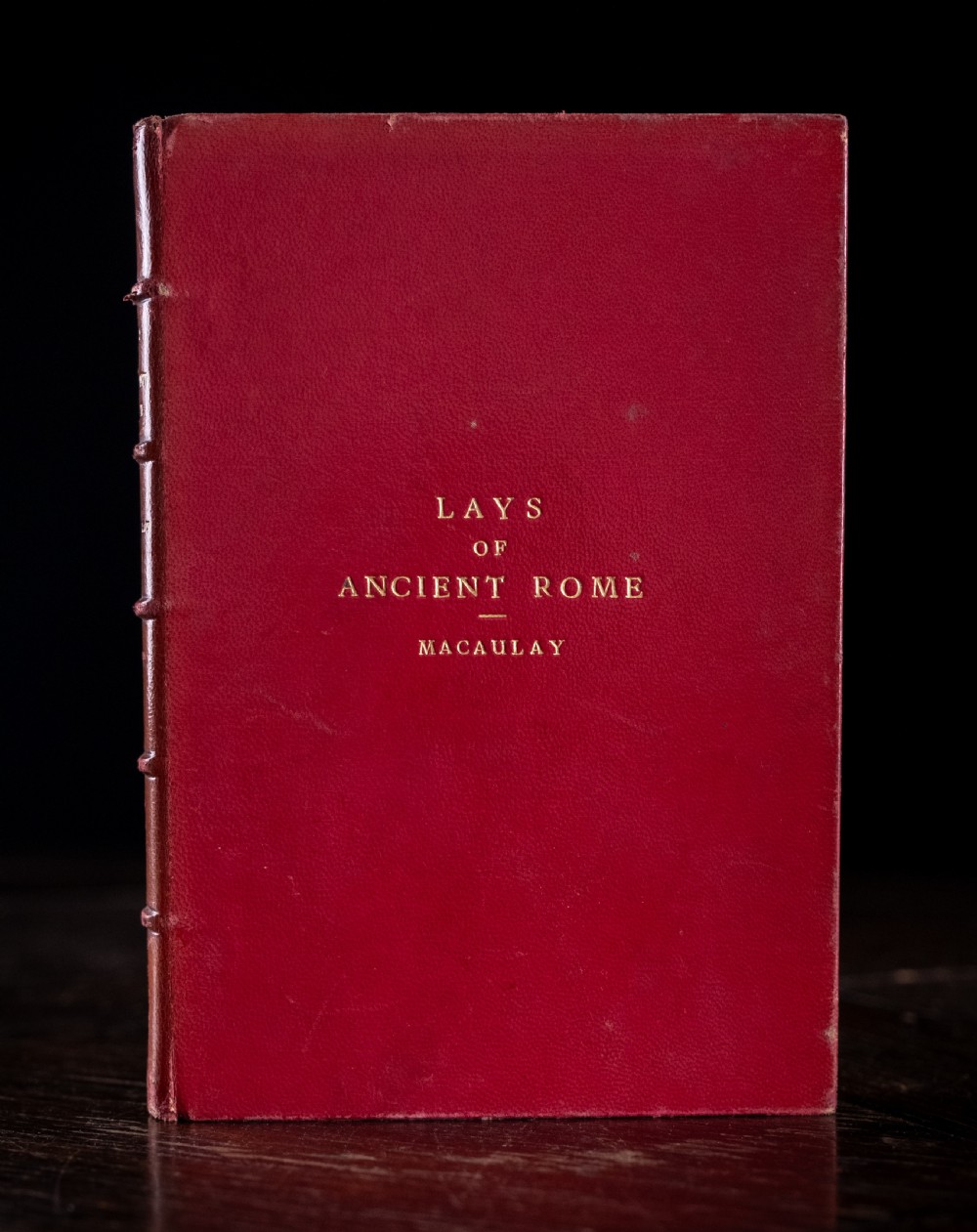A red leather-bound edition of Lays of Ancient Rome by Macaulay, featuring raised spine bands and gilt lettering. View III