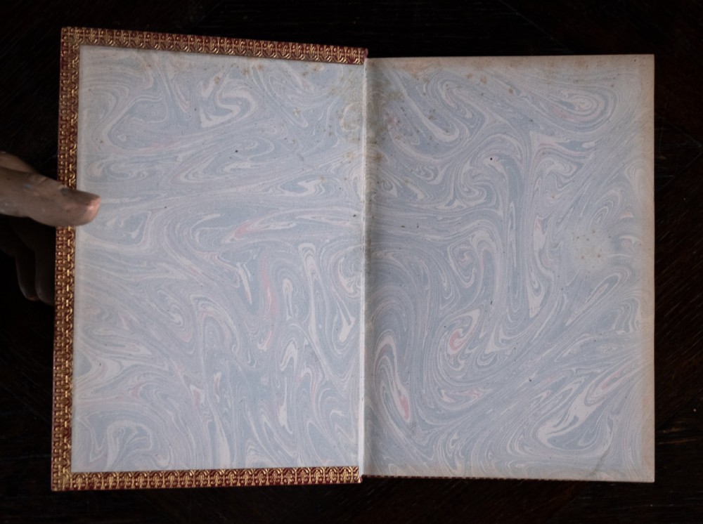 A red leather-bound edition of Lays of Ancient Rome by Macaulay, featuring raised spine bands and gilt lettering. View V