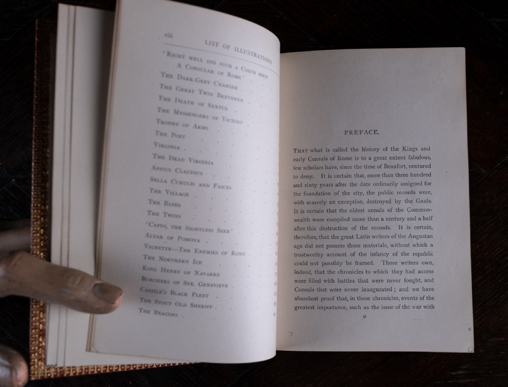 A red leather-bound edition of Lays of Ancient Rome by Macaulay, featuring raised spine bands and gilt lettering. View XII