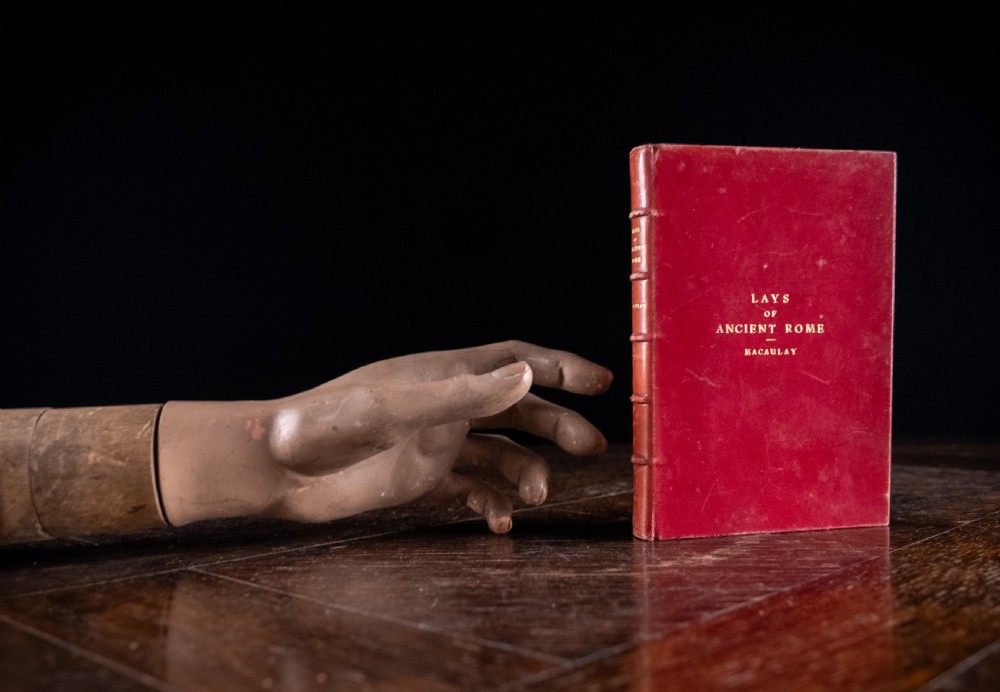 A red leather-bound edition of Lays of Ancient Rome by Macaulay, featuring raised spine bands and gilt lettering. View XIII