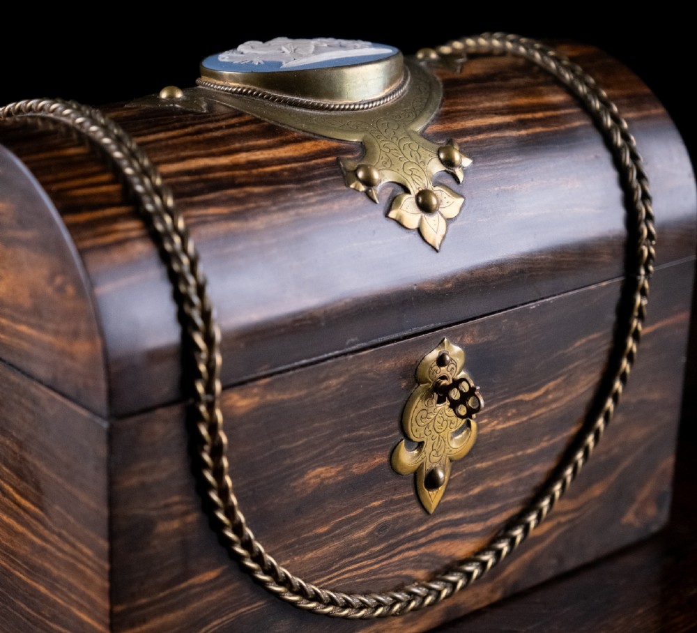 A Victorian domed coromandel wood casket featuring a central blue jasperware cameo medallion set within engraved brass mounts and a twisted brass border. View II