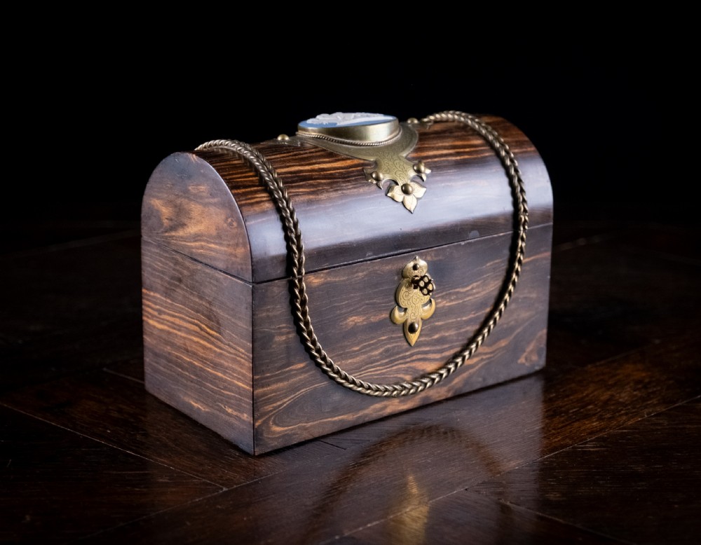 A Victorian domed coromandel wood casket featuring a central blue jasperware cameo medallion set within engraved brass mounts and a twisted brass border.