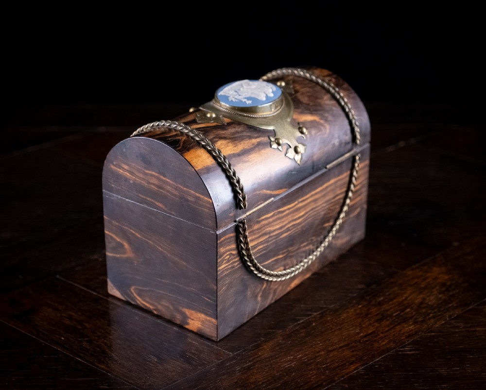 A Victorian domed coromandel wood casket featuring a central blue jasperware cameo medallion set within engraved brass mounts and a twisted brass border. View IX