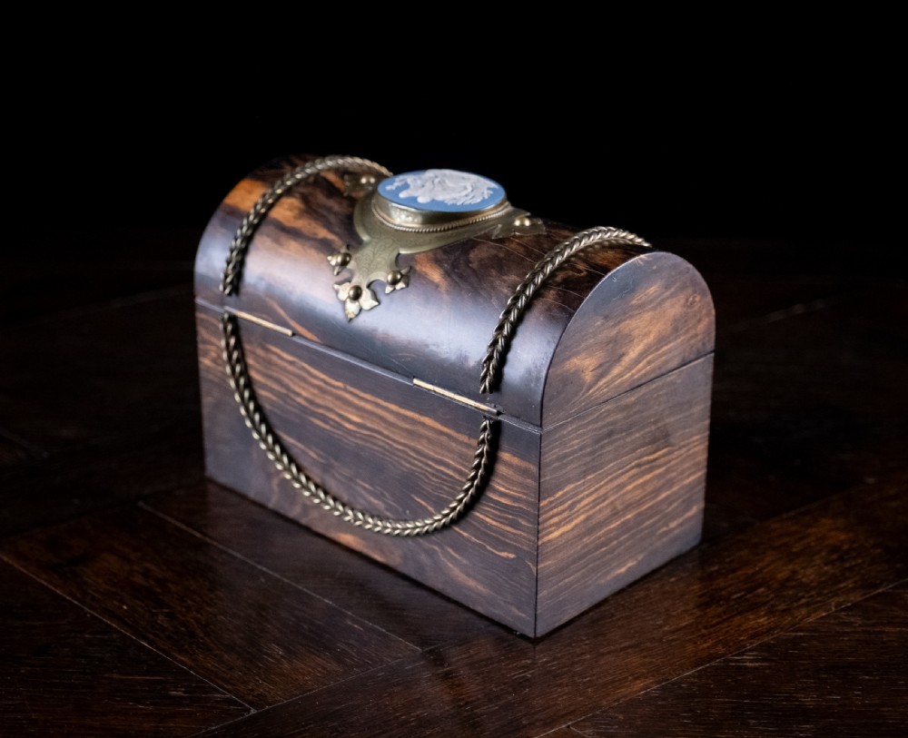 A Victorian domed coromandel wood casket featuring a central blue jasperware cameo medallion set within engraved brass mounts and a twisted brass border. View XII