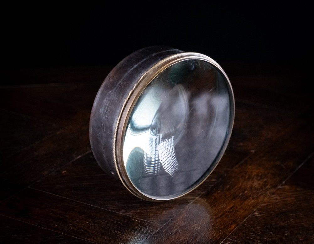 A Victorian cylindrical desktop magnifier featuring a thick circular glass convex lens set within a heavy metal rim. View II
