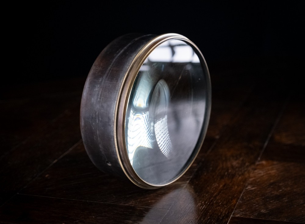 A Victorian cylindrical desktop magnifier featuring a thick circular glass convex lens set within a heavy metal rim. View III