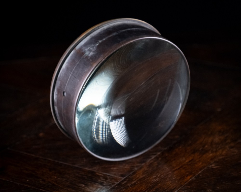 A Victorian cylindrical desktop magnifier featuring a thick circular glass convex lens set within a heavy metal rim. View IV