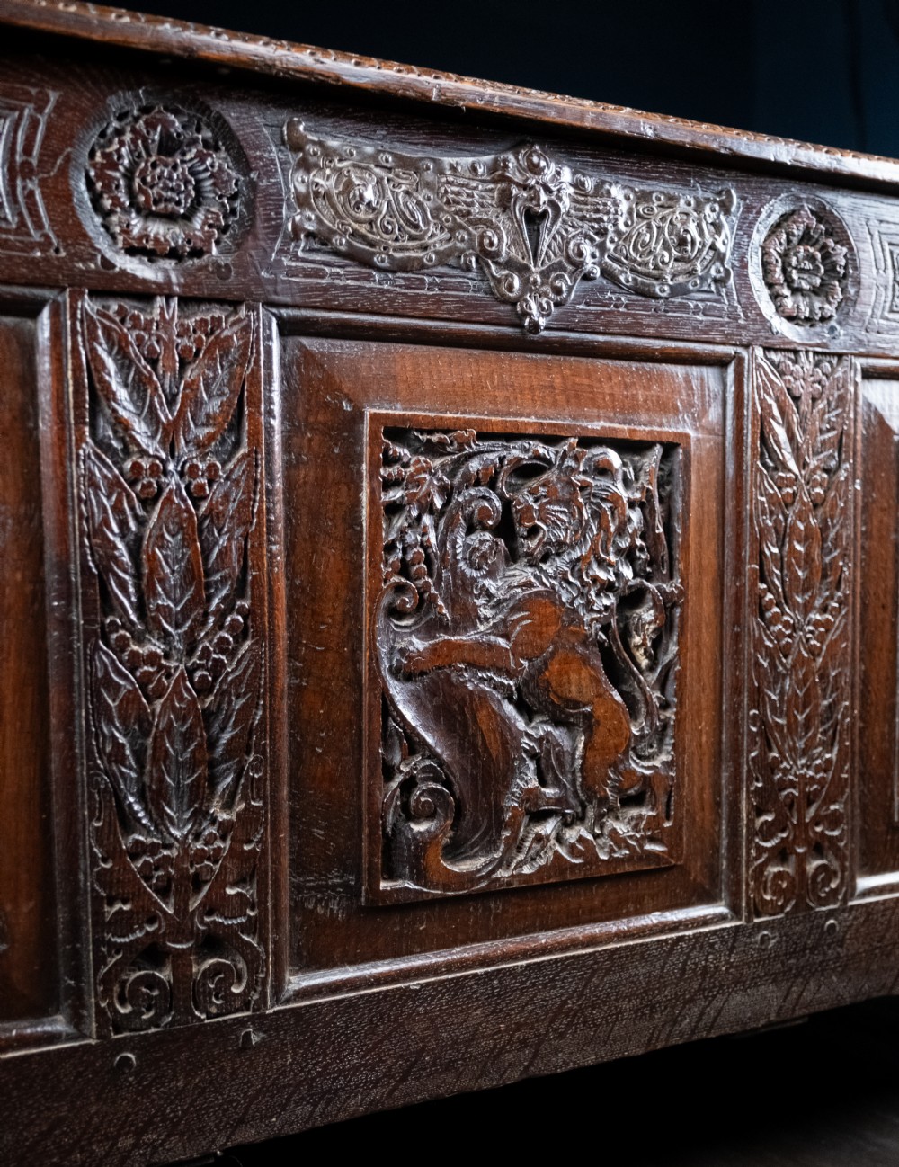 A 17th-century dark oak coffer featuring three carved panels with a central lion motif and geometric rosettes. View II