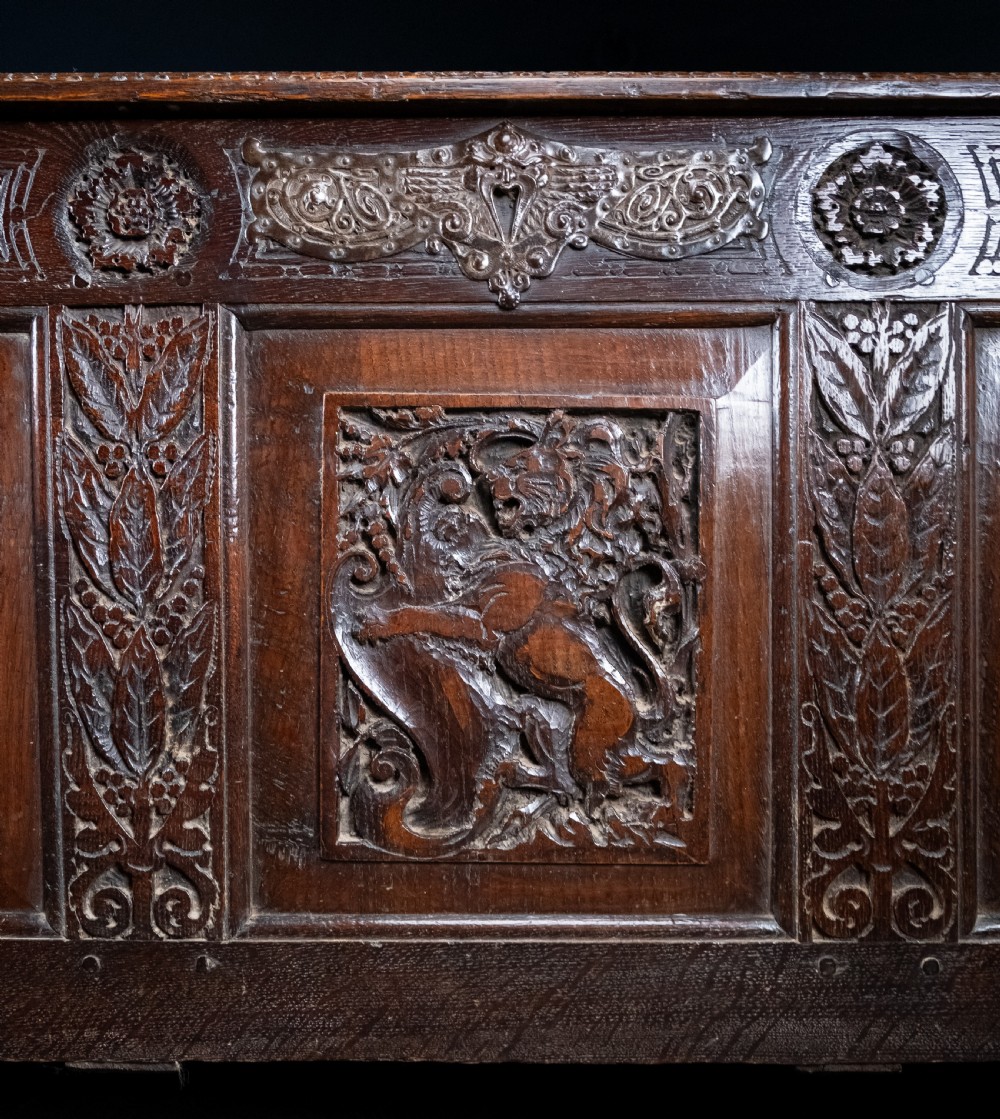 A 17th-century dark oak coffer featuring three carved panels with a central lion motif and geometric rosettes. View III