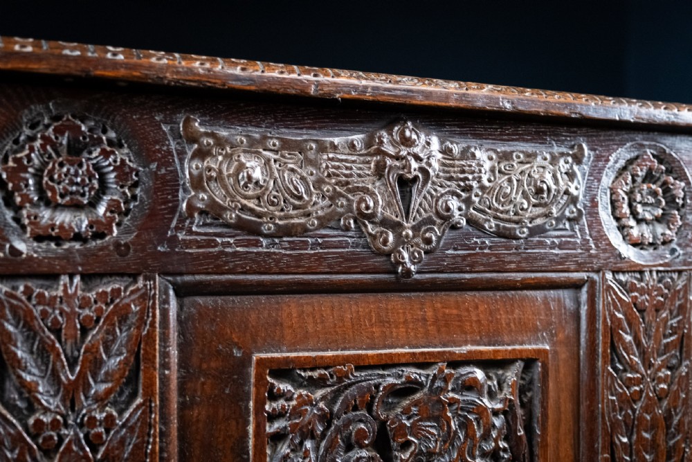 A 17th-century dark oak coffer featuring three carved panels with a central lion motif and geometric rosettes. View IV