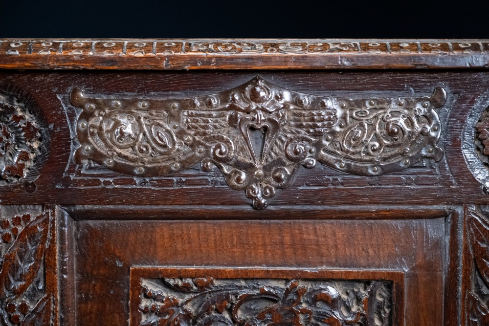 A 17th-century dark oak coffer featuring three carved panels with a central lion motif and geometric rosettes. View V