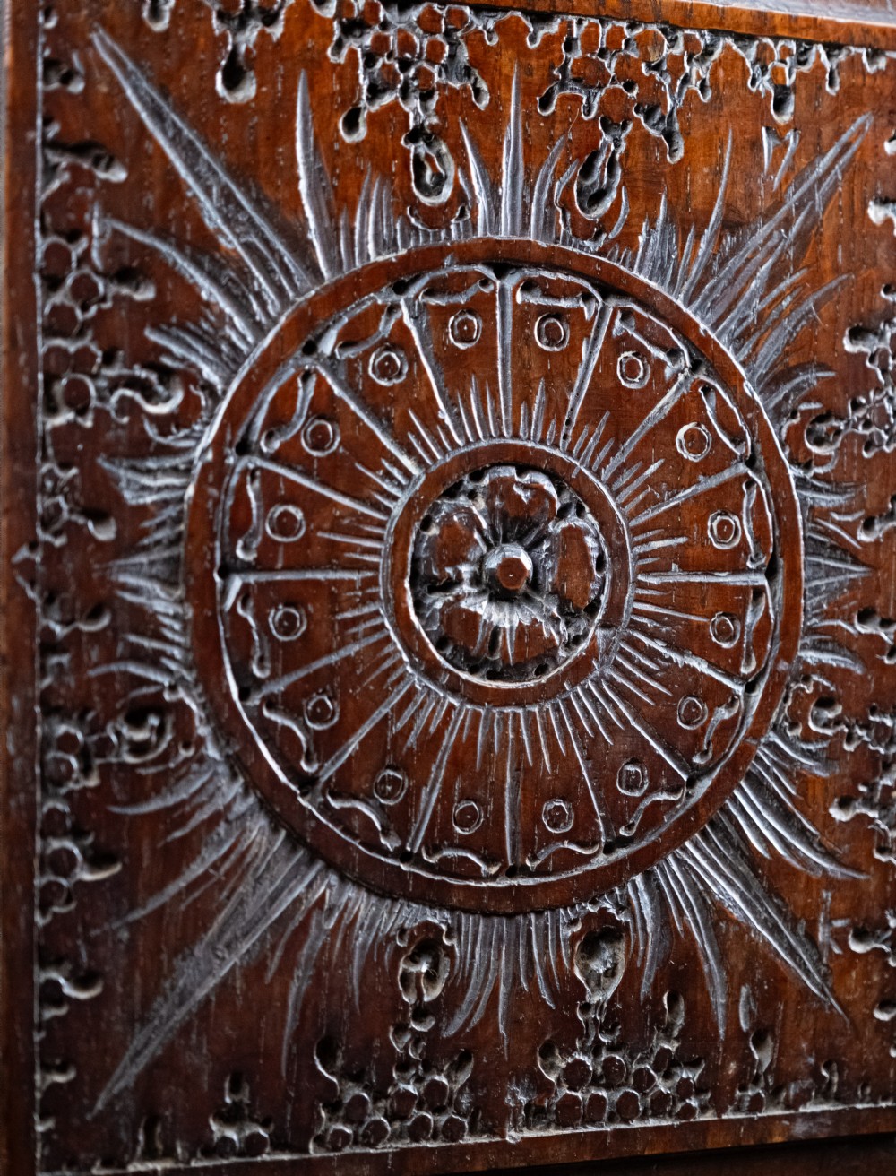 A 17th-century dark oak coffer featuring three carved panels with a central lion motif and geometric rosettes. View VII
