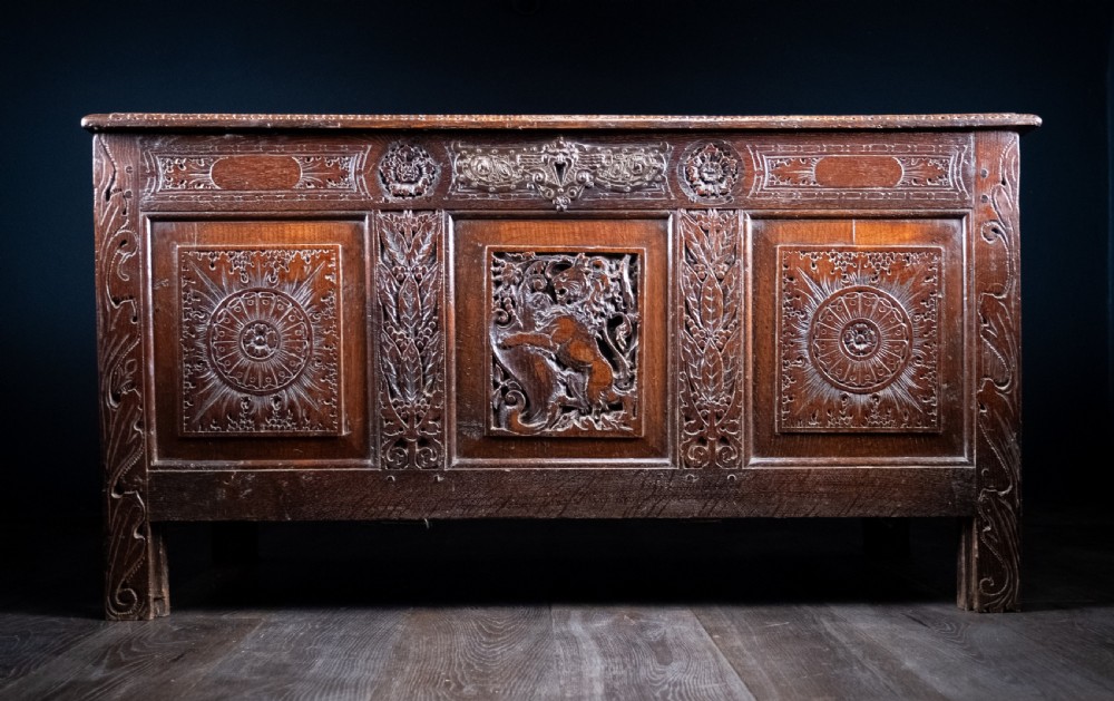 A 17th-century dark oak coffer featuring three carved panels with a central lion motif and geometric rosettes. View VIII
