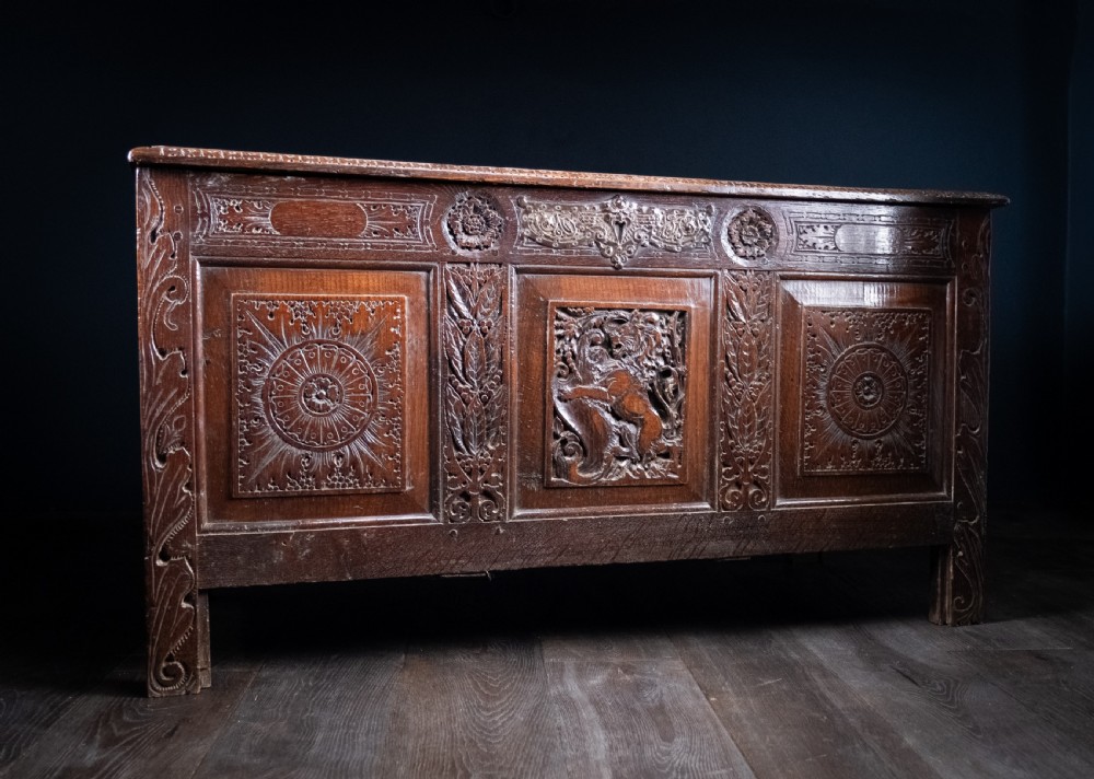 A 17th-century dark oak coffer featuring three carved panels with a central lion motif and geometric rosettes. View IX