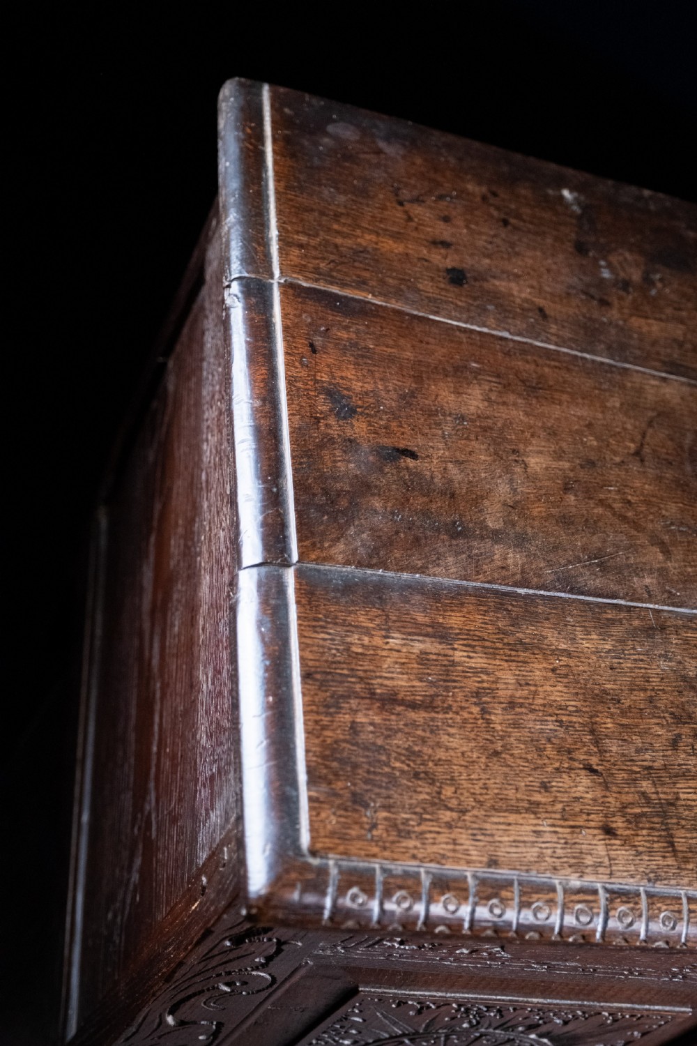 A 17th-century dark oak coffer featuring three carved panels with a central lion motif and geometric rosettes. View XII