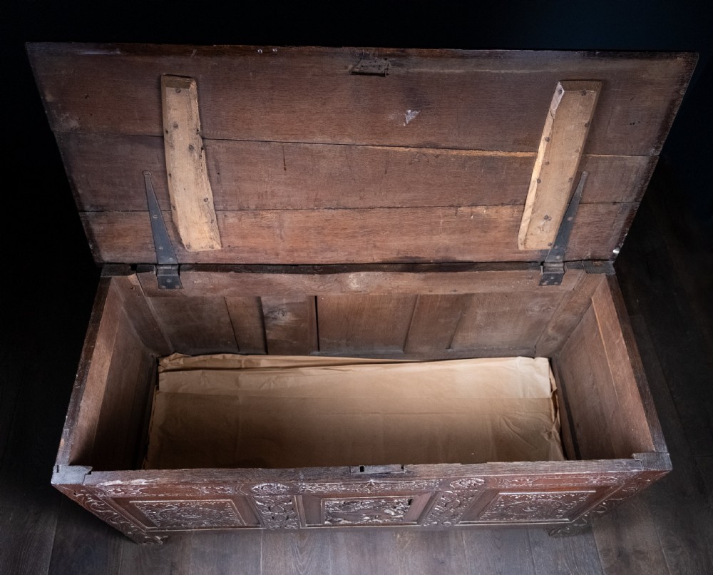 A 17th-century dark oak coffer featuring three carved panels with a central lion motif and geometric rosettes. View XVI