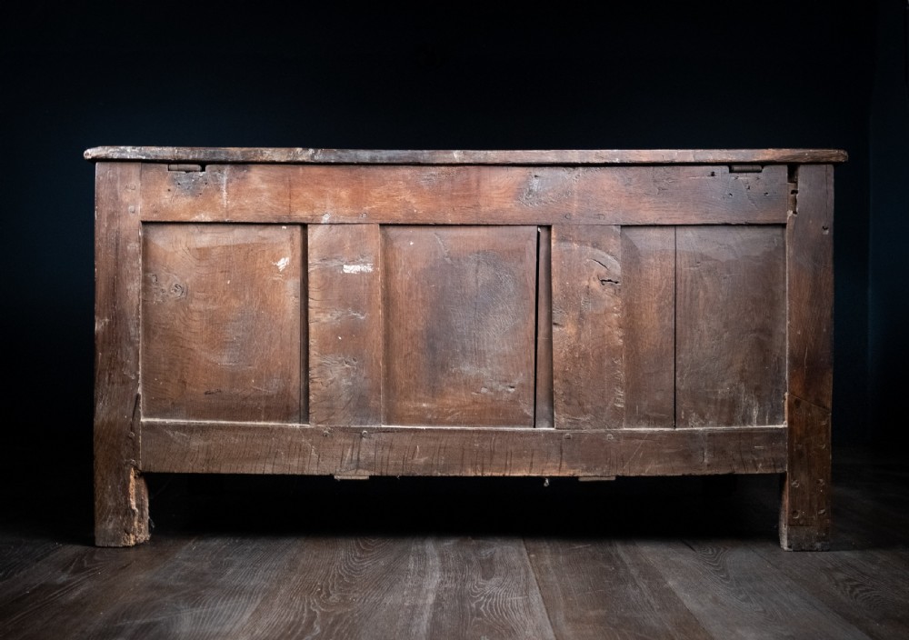 A 17th-century dark oak coffer featuring three carved panels with a central lion motif and geometric rosettes. View XX