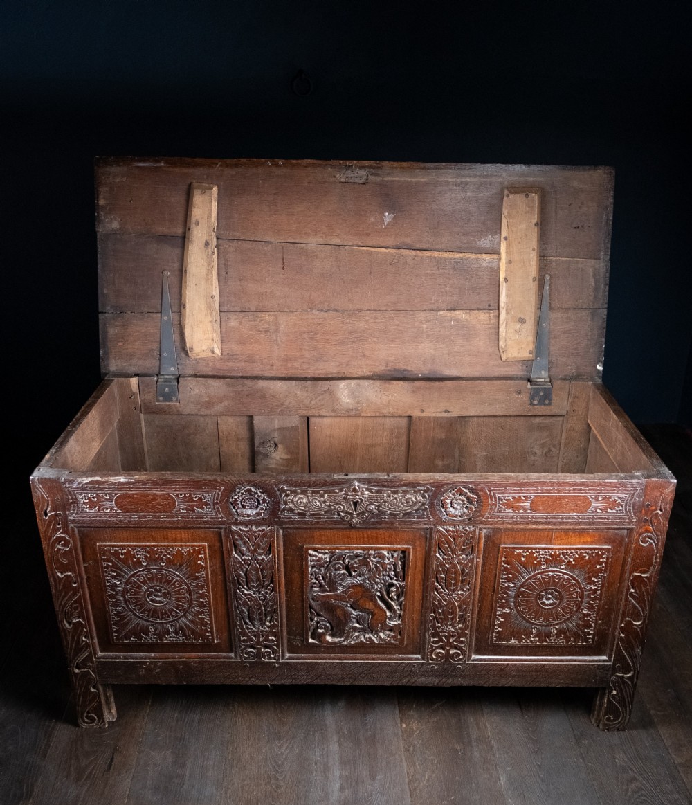 A 17th-century dark oak coffer featuring three carved panels with a central lion motif and geometric rosettes. View XXIV
