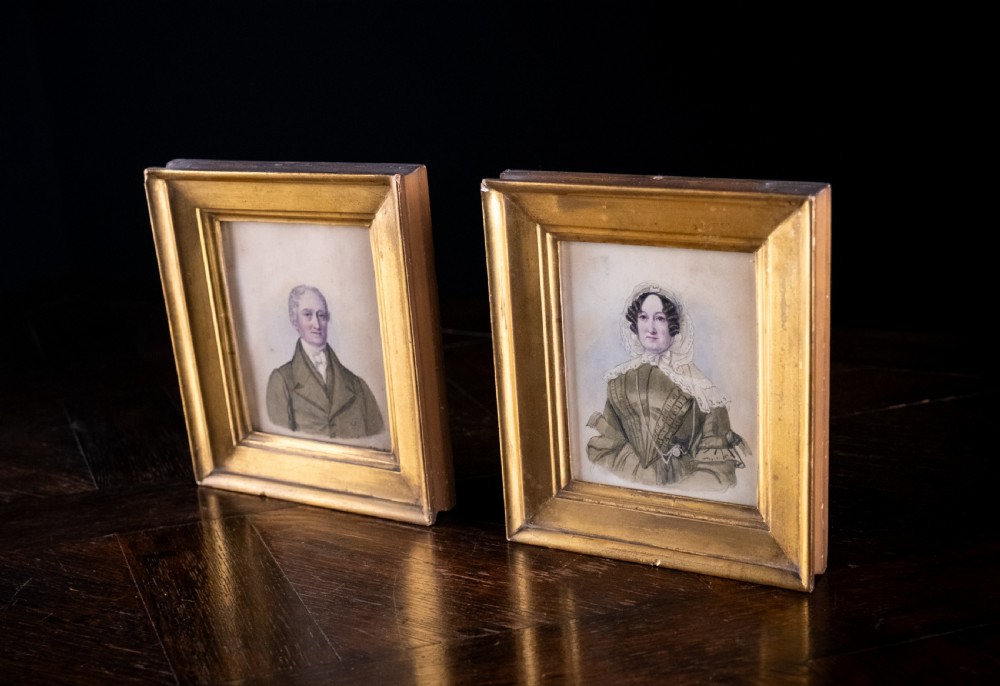 A pair of early 19th-century watercolour portrait paintings featuring a gentleman and a lady set within thick moulded giltwood frames. View X