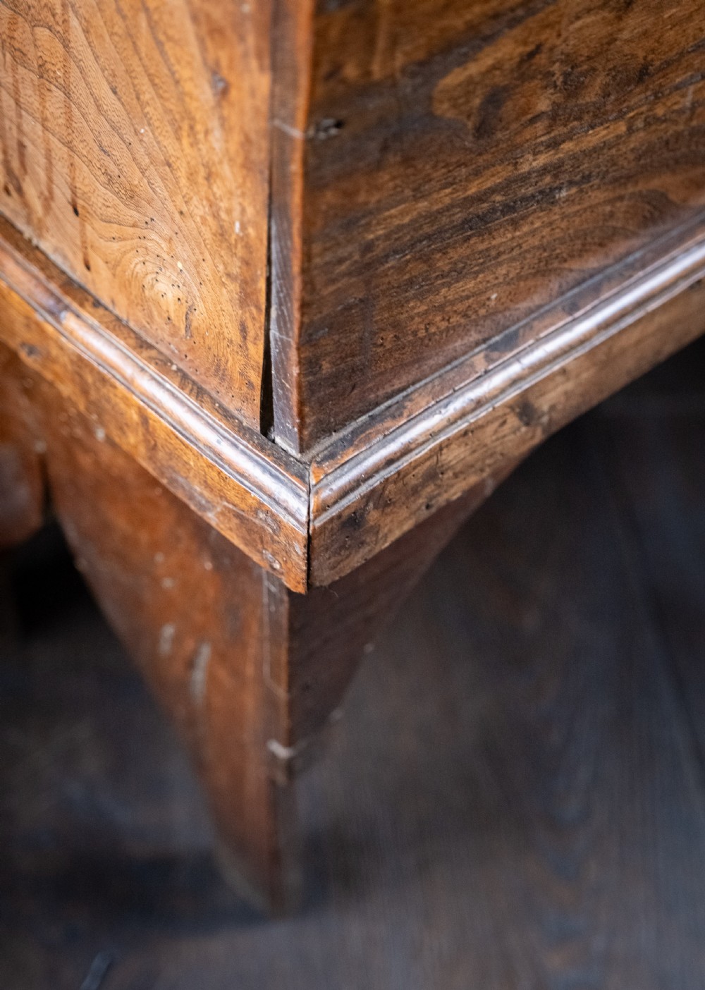 A seventeenth-century elm six-plank coffer featuring a hinged lid, raised bootjack side ends, and visible grain patterns against a dark background. View VIII