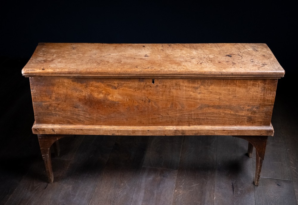 A seventeenth-century elm six-plank coffer featuring a hinged lid, raised bootjack side ends, and visible grain patterns against a dark background. View XIII