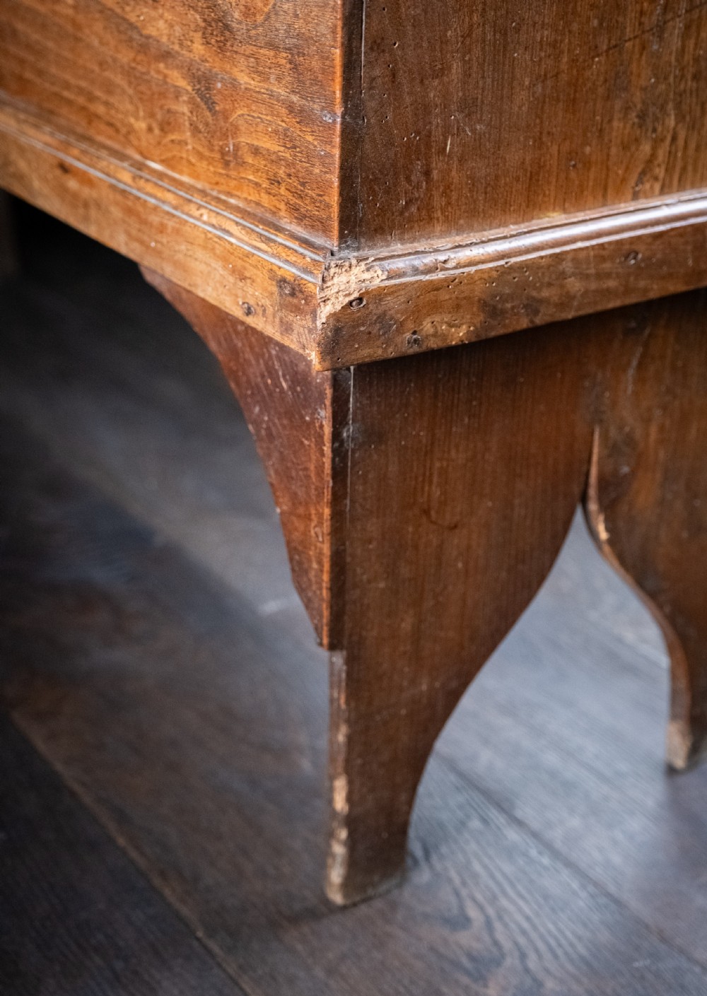 A seventeenth-century elm six-plank coffer featuring a hinged lid, raised bootjack side ends, and visible grain patterns against a dark background. View XVIII