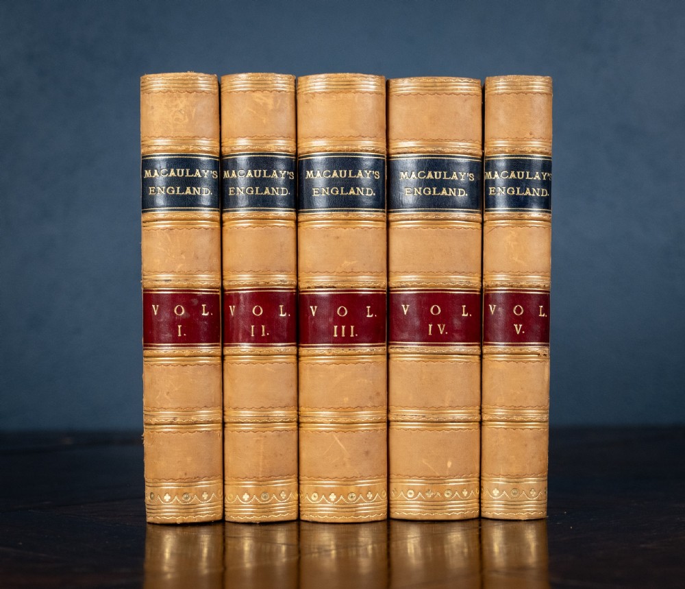 A five-volume set of Victorian leather-bound books with tan calfskin spines, gilt tooling, and contrasting red and navy spine labels standing vertically.