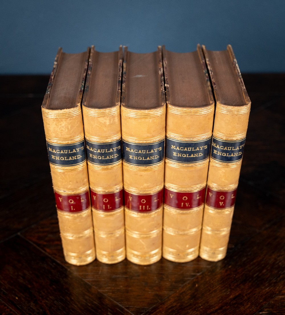 A five-volume set of Victorian leather-bound books with tan calfskin spines, gilt tooling, and contrasting red and navy spine labels standing vertically. View IV