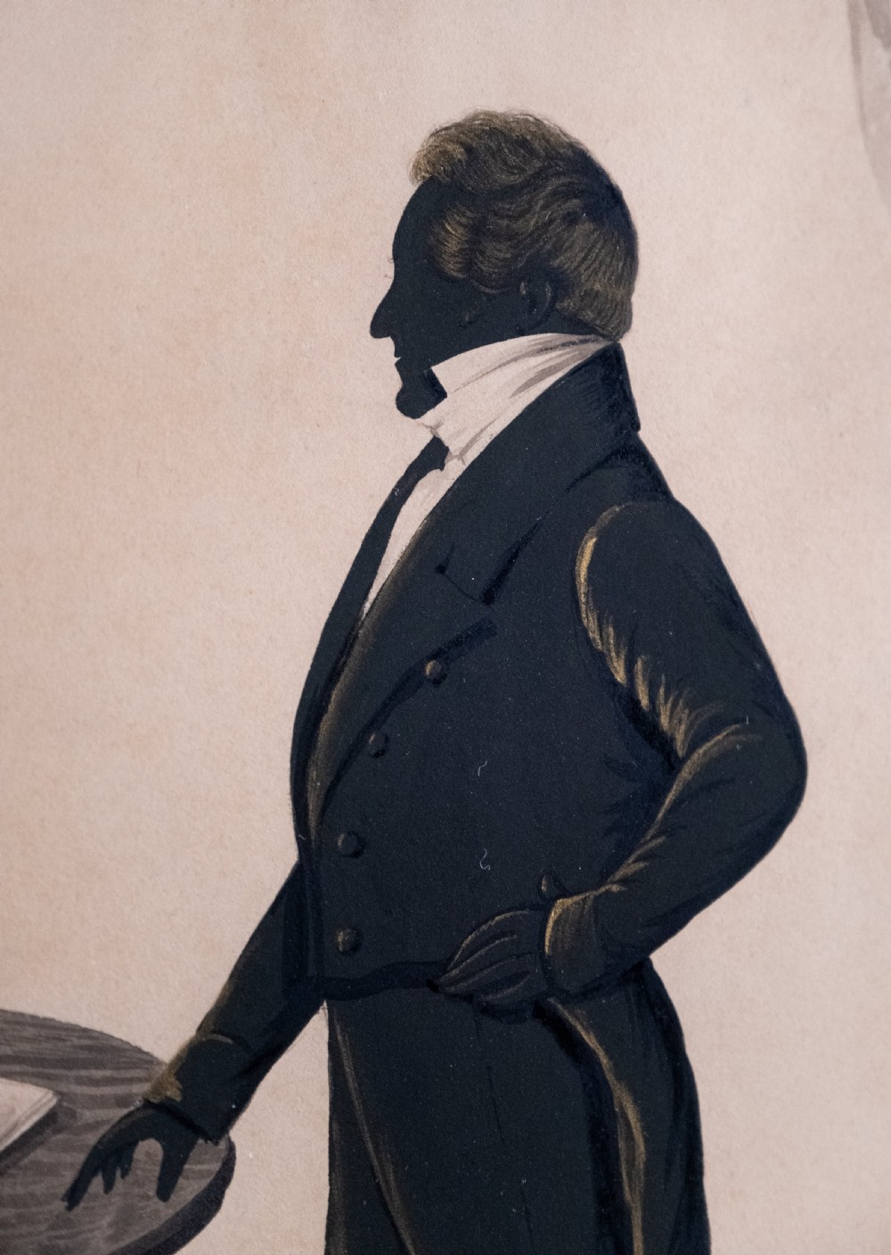 A framed full-length Regency silhouette portrait depicting a gentleman in profile standing beside a table with a draped curtain in the background. View III