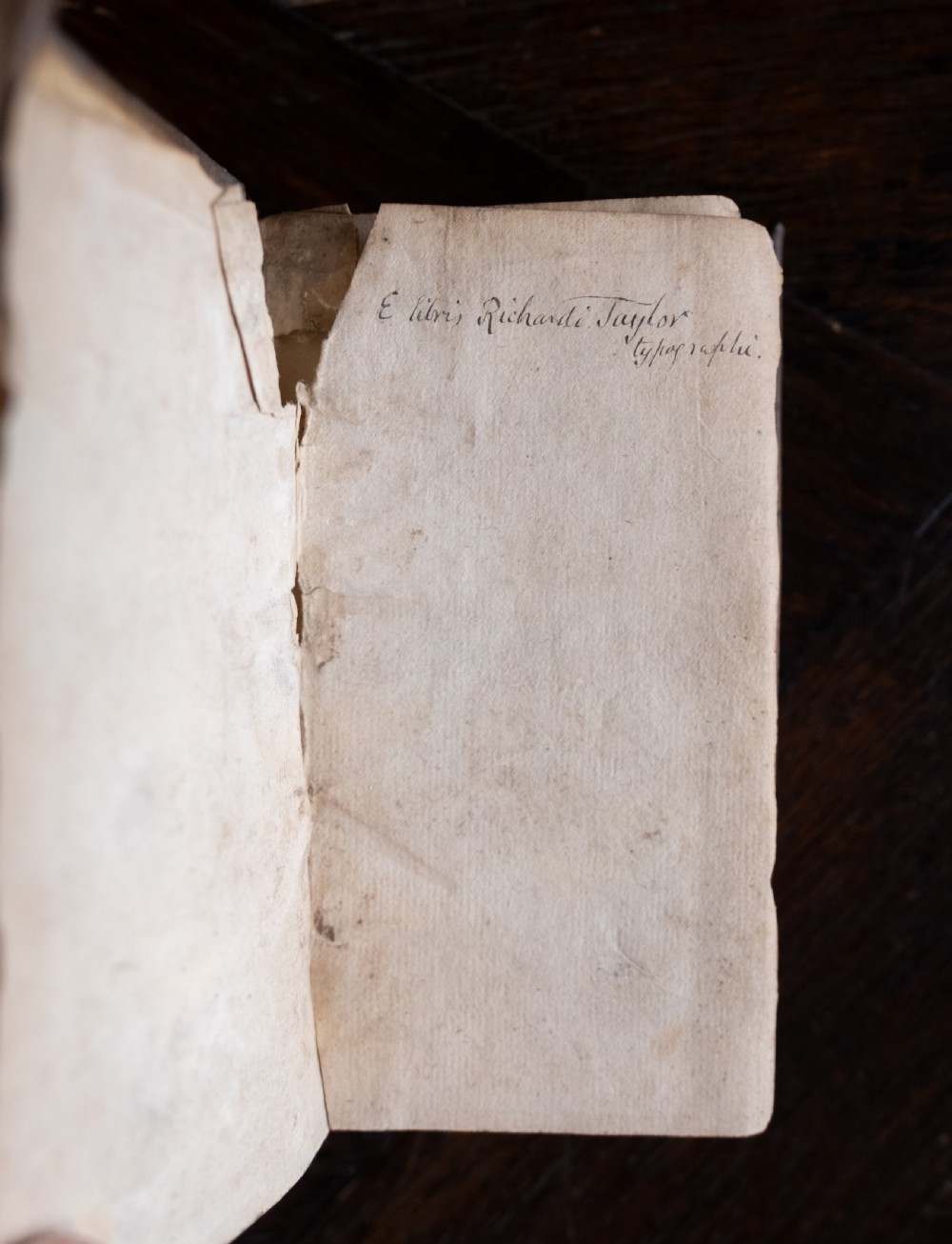A 17th-century vellum-bound book standing upright with handwritten Latin text on the spine. View VI