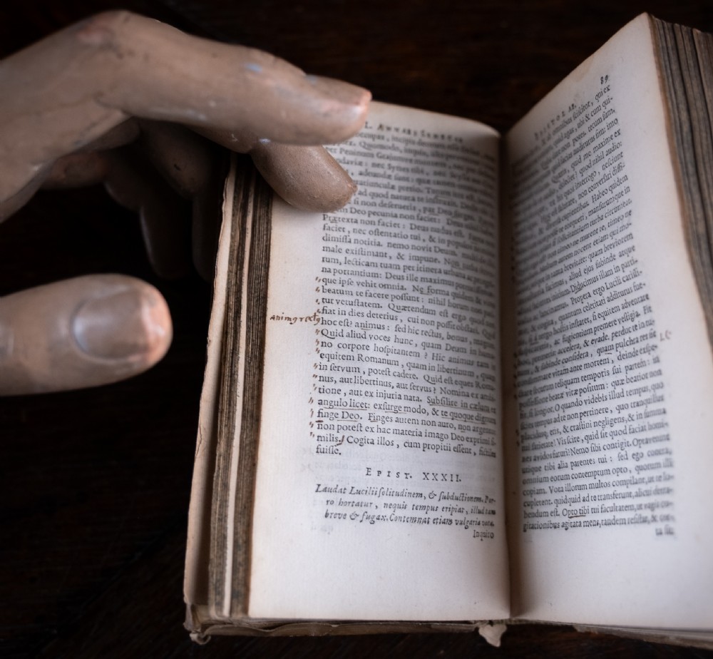 A 17th-century vellum-bound book standing upright with handwritten Latin text on the spine. View X