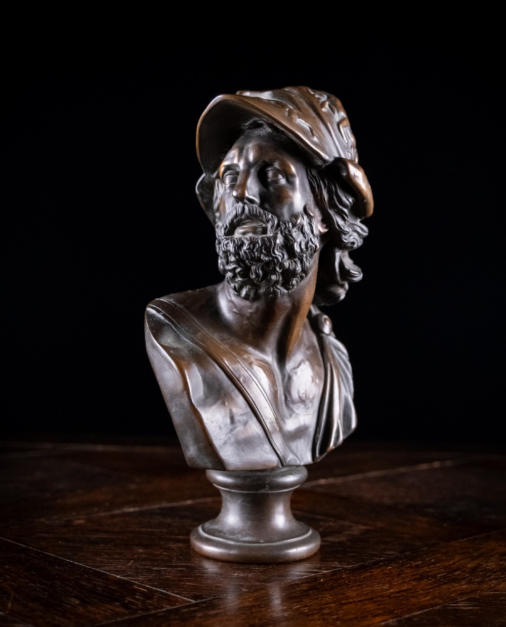 A patinated dark brown French bronze bust depicting the classical figure of Ajax wearing a detailed helmet, set upon a turned circular pedestal. View II