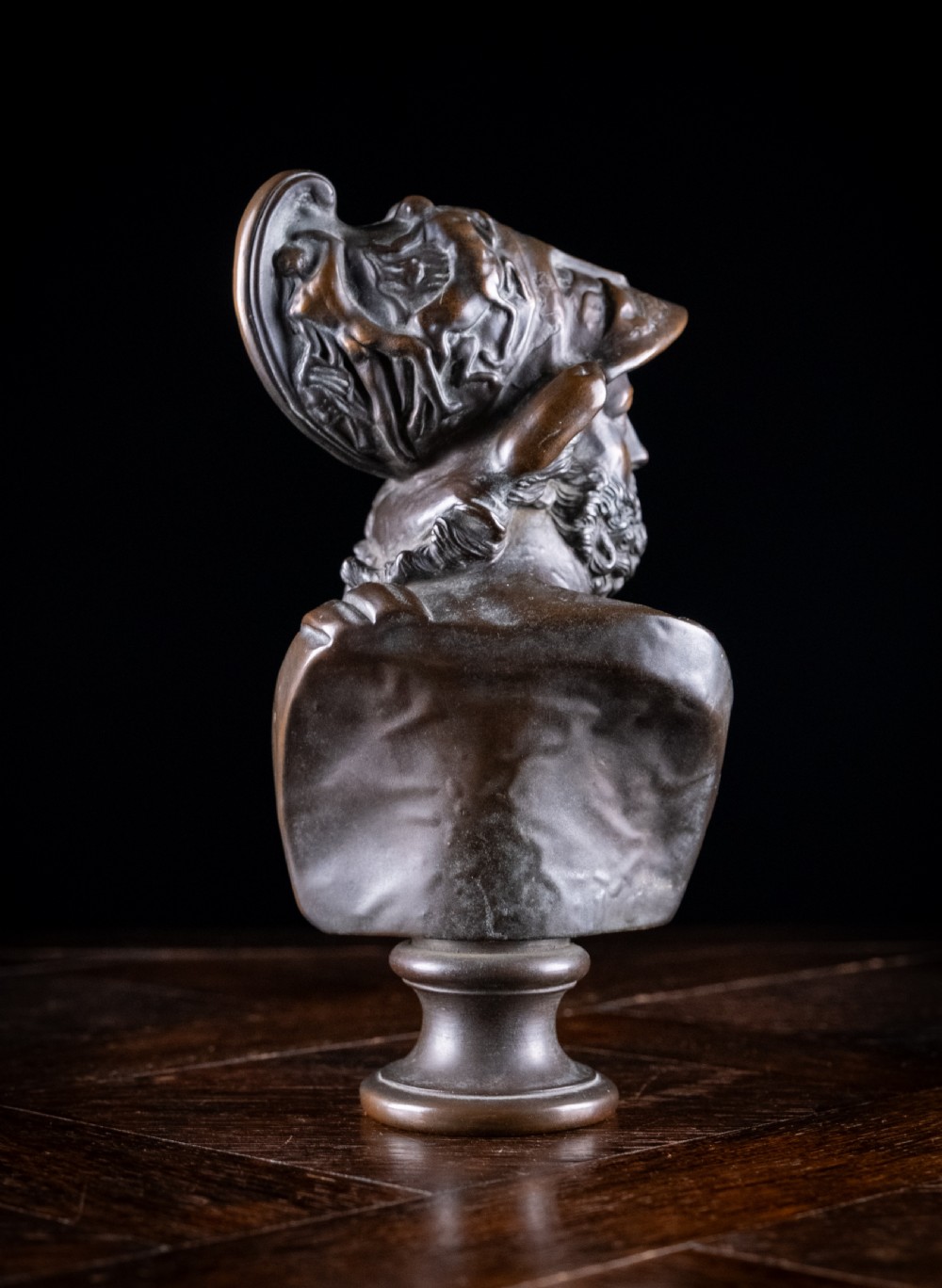 A patinated dark brown French bronze bust depicting the classical figure of Ajax wearing a detailed helmet, set upon a turned circular pedestal. View IV