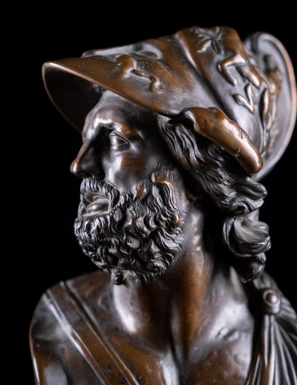 A patinated dark brown French bronze bust depicting the classical figure of Ajax wearing a detailed helmet, set upon a turned circular pedestal. View VIII