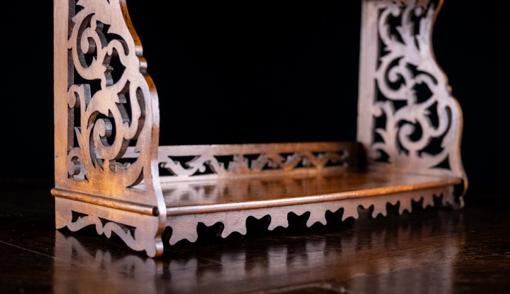 A three-tier Victorian mahogany wall shelf featuring open fretwork sides, pierced scroll decoration, and serrated apron trim. View IV